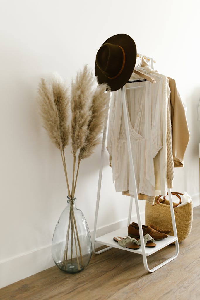 A stylish apparel display with pampas grass, hat, and shoes in a modern room.