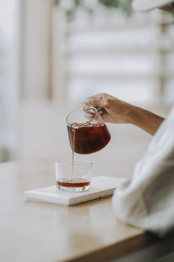 Aesthetic shot of fresh coffee being poured into glass on a wooden counter in Bali.